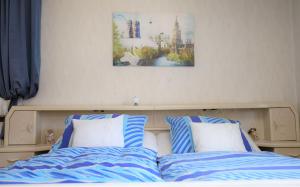uma cama com almofadas azuis e brancas e uma fotografia na parede em Ferienwohnung Röhrer em Obertrubach