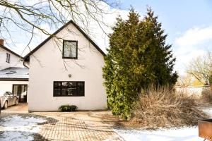 una casa blanca con un árbol delante en Garden View Home, en Mārupe