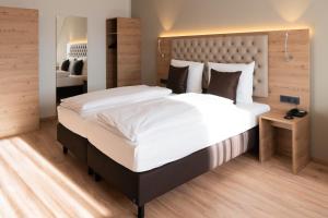 um quarto com uma cama grande e uma grande cabeceira. em Rossano Boutique Hotel & Ristorante em Ansbach