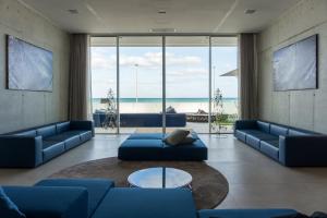 a living room with blue couches and a view of the ocean at Posia Retreat & Spa UNA Esperienze in San Foca
