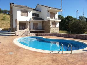 a villa with a swimming pool in front of a house at Casa la hijita in Navaluenga