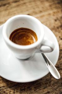 a cup of coffee on a white plate on a table at Rossano Boutique Hotel & Ristorante in Ansbach