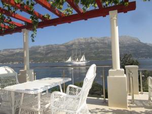 a patio with a table and chairs and a boat in the water at Vila Tea in Korčula