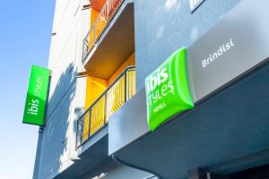 una tienda con dos letreros verdes a un lado de un edificio en Ibis Styles Brindisi, en Brindisi