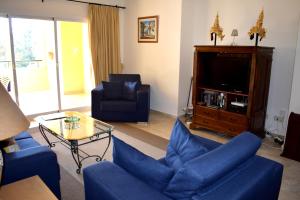 uma sala de estar com sofás azuis e uma televisão em Greenlife Village Apartment em Marbella