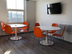 een wachtkamer met 2 tafels en oranje stoelen bij No57 in Crewe