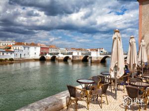 a group of chairs and umbrellas next to a river at le Boucanier in Tavira