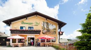 budynek ze stołami i parasolami przed nim w obiekcie Braunegger-Hof Gasthof Mayer w mieście Braunegg