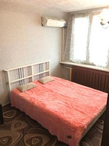 モスクワにあるアパートメント G クヴァルタル レニングラーツキーのベッドルーム1室(赤い掛け布団、窓付)
