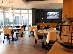 a restaurant with tables and chairs and a tv at Hotel Kyriad Tours St Pierre des Corps Gare in Saint-Pierre-des-Corps