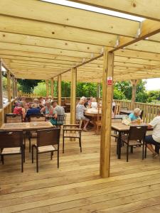 un groupe de personnes assises à des tables sur une terrasse en bois dans l'établissement The Rivers Arms, à Dorchester