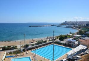 a large swimming pool next to a beach and the ocean at Lianos Apartments Business Class A in Piraeus