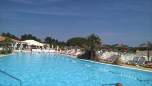 a large blue swimming pool with chairs and umbrellas at Village Vacances 4 etoiles LES MATHES AUX CHARMETTES in Les Mathes
