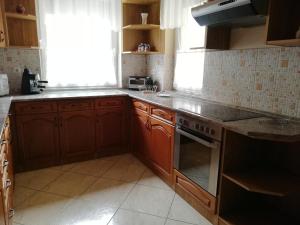 cocina con armarios de madera y horno con fogones en Imola És Andrea Apartmanház, en Hajdúszoboszló