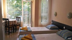 a bedroom with two beds and a table and windows at На гости при Силвия in Obzor