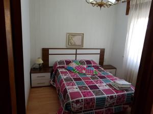 a bedroom with a bed with a quilt on it at HOSTAL BODEGÓN A COSECHA in San Ciprián