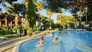 zwei Personen schwimmen in einem Pool in einem Resort in der Unterkunft Entre mer et piscine in Hyères