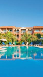 ein großer Pool mit einem Resort im Hintergrund in der Unterkunft Entre mer et piscine in Hyères