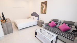 ein Wohnzimmer mit einem Sofa und einem Bett mit rosa Kissen in der Unterkunft White Diamond Hotel - Airport in Ho-Chi-Minh-Stadt