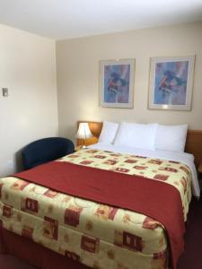 um quarto de hotel com uma cama com um cobertor vermelho em Trunk Road Motel em Sault Ste. Marie