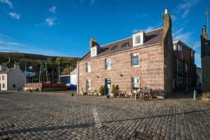 a large brick building on a cobblestone street at Shorehead Guest House in Stonehaven