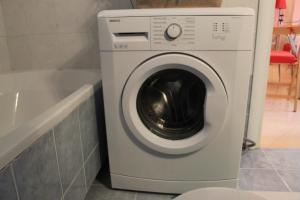 Una lavadora en un baño al lado de una bañera. en Paradise, en Tolo