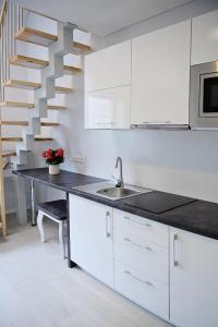 uma cozinha com armários brancos e uma escadaria em Lofts - Kaunas airport em Karmėlava