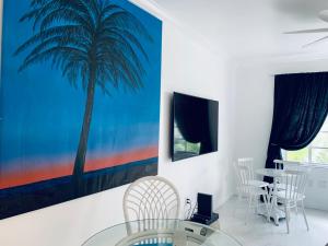 een eetkamer met een schilderij van palmbomen aan de muur bij Luxury white loft on Ocean Drive-South beach with a view in Miami Beach