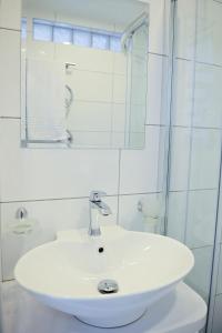 a white bathroom with a sink and a mirror at Lofts - Kaunas airport in Karmėlava