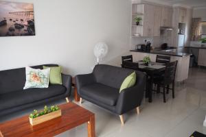 OR Tambo Self Catering Apartments, The Willows في بوكسبرغ: غرفة معيشة مع أريكة وكرسي وطاولة