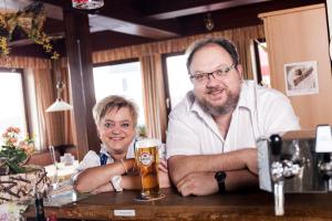 a man and a woman sitting at a bar with a beer at Braunegger-Hof Gasthof Mayer in Braunegg