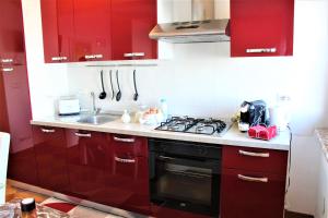 a kitchen with red cabinets and a stove top oven at Villa Sofia in Taormina