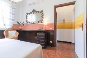 een slaapkamer met een bed, een spiegel en een stoel bij Il nido del pavone in Monterosso al Mare