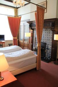 a bedroom with a bed with curtains and a fireplace at De Doelen in Leiden