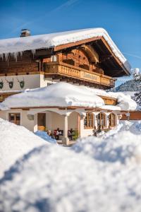 ein Haus voller Schnee in den Bergen in der Unterkunft Hotel Garni Ransburgerhof in Flachau