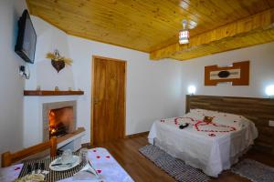 a bedroom with a bed and a fireplace at Pousada Varanda Colibri in Monte Verde