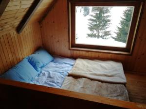 a small bed in a room with a window at Koliba - Prokoško jezero in Fojnica