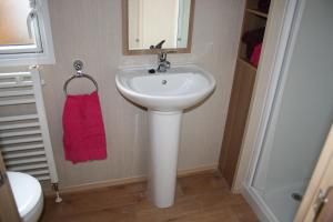 a bathroom with a white sink and a red towel at Chalet 10 Dornoch Pitgrudy in Dornoch