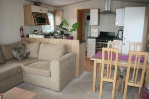ein Wohnzimmer und eine Küche mit einem Sofa und einem Tisch in der Unterkunft Chalet 10 Dornoch Pitgrudy in Dornoch