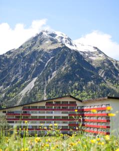a building in front of a snow covered mountain at Aparthotel Kleinwalsertal in Mittelberg