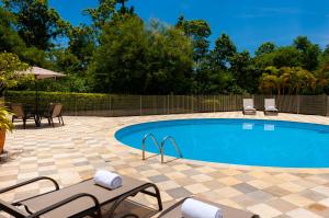 a swimming pool with two chairs and a table and chairs at Matiz Barão Geraldo Express Hotel in Campinas