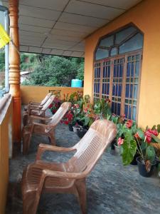 eine Gruppe von Stühlen auf einer Veranda mit Blumen in der Unterkunft Ohiya Mount Plaza in Boralanda