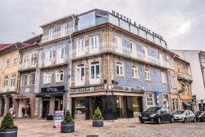 a large blue building with white windows on a street at In Barcelos Hostel & Guest House in Barcelos