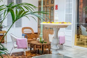 um pátio com cadeiras, uma mesa e uma fonte em Hotel Madinat em Córdoba