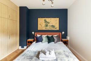 a bedroom with blue walls and a bed with two towels at The Lempicka 2 Bedroom Flat and Garden in Notting Hill in London