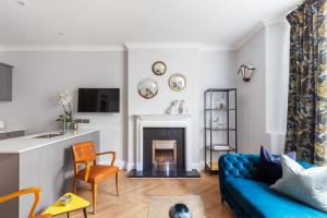 a living room with a blue couch and a fireplace at The Lempicka 2 Bedroom Flat and Garden in Notting Hill in London