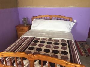 a bed with a wooden headboard in a purple bedroom at Gîte d'étape traditionnel berbère in Ifri