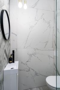 a bathroom with white marble walls and a mirror at Elite Apartments Old Town Premium in Gdańsk