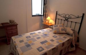 1 dormitorio con 1 cama con edredón y ventana en Cala Apartamentos, en Giniginámar