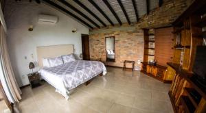 1 dormitorio con 1 cama grande y pared de ladrillo en Hotel Tata Premium, en Pueblo Tapado